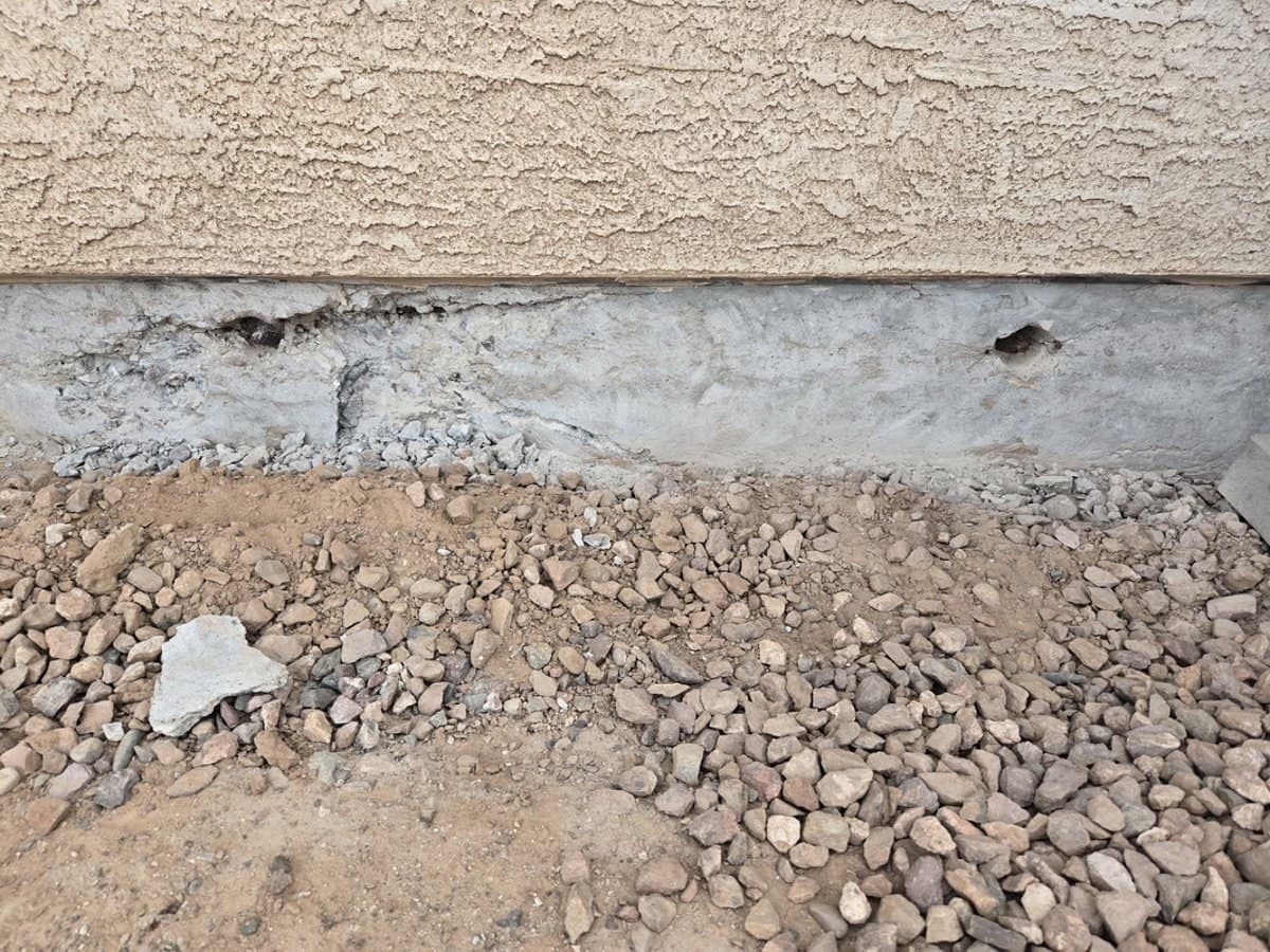 Slab edge with damaged concrete chipped out to expose post-tension anchors
